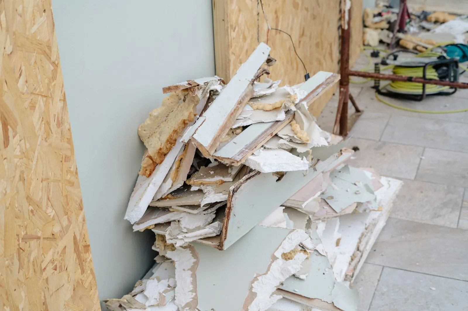 Symbolbild: Gipsplatten-Reste und Bauabfall an einer Wand auf einer Baustelle
