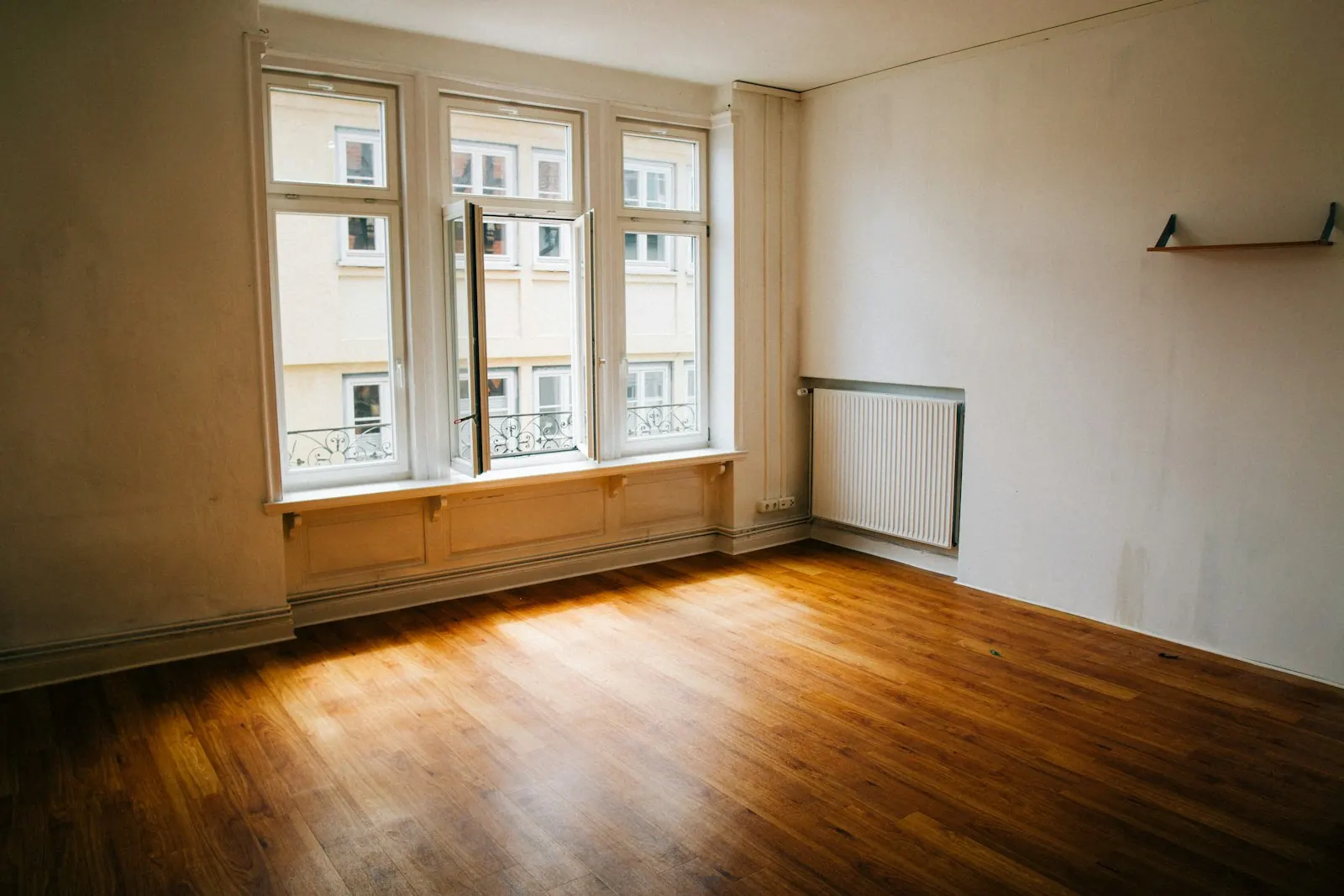 Symbolbild: leeres, helles Zimmer mit Parkettboden und grossen Fenstern